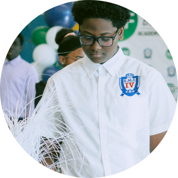 A person wearing glasses and a white shirt with an "RMS IV" logo stands in front of a backdrop with various logos and balloons.