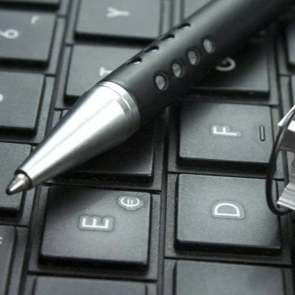 A black pen rests on a keyboard, near the E, F, and D keys.