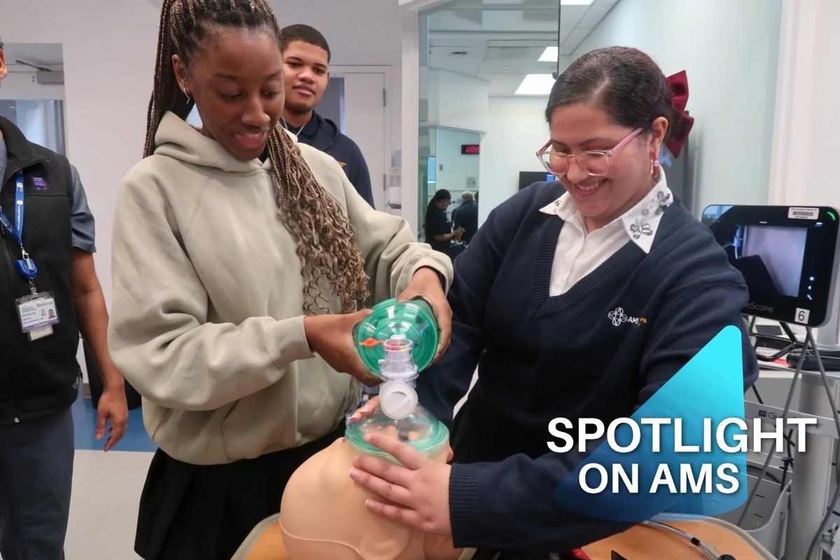 Two people practice CPR on a medical mannequin in a lab setting. One holds the mask, while the other assists. A "Spotlight on AMS" label is visible.