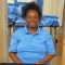 A staff member of United Charter High Schools wears a blue uniform shirt. She is sitting at a table with a selection of blue uniform shirts.
