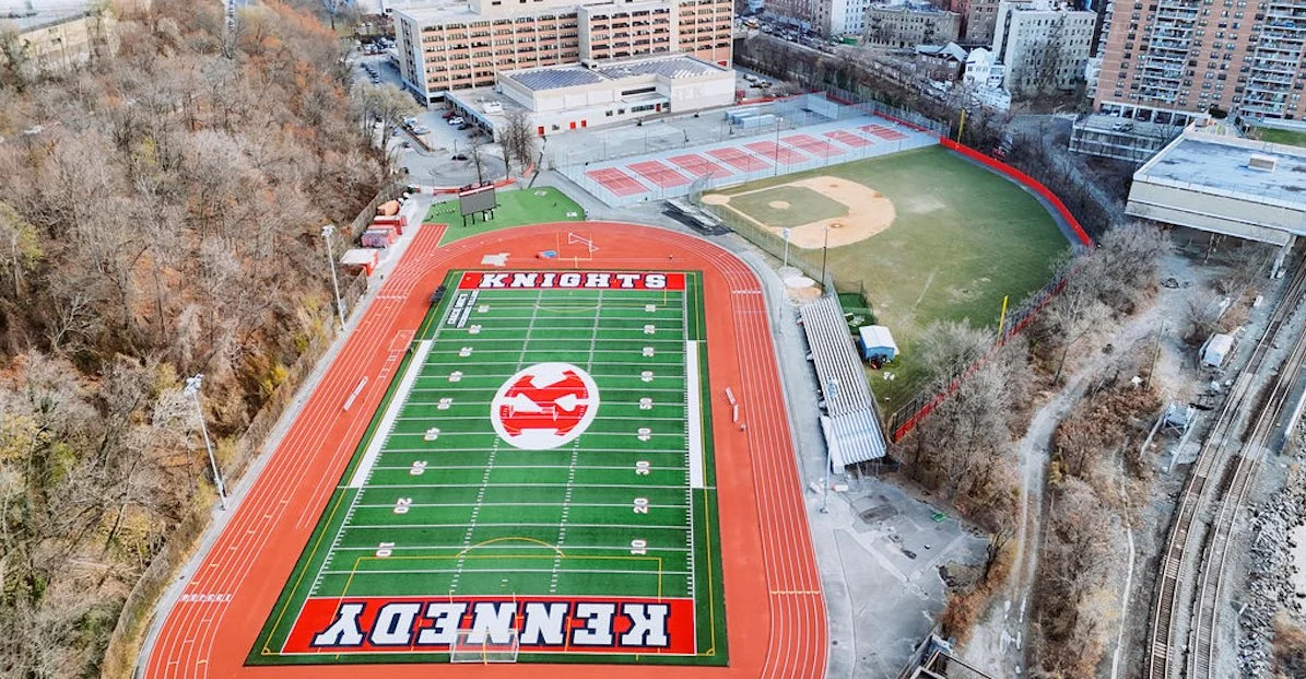 Aerial view of a sports complex with a football field labeled "KENNEDY KNIGHTS," a baseball diamond, multiple tennis courts, and surrounding buildings and trees.