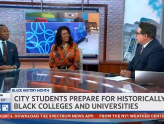 Three news anchors sit at a studio desk discussing Black History Month, with a headline about city students preparing for historically Black colleges and universities displayed on screen.
