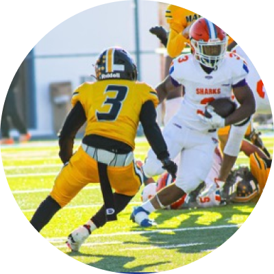 A football player in a white "Sharks" uniform runs with the ball while being pursued by a player in a yellow and black uniform numbered 3.