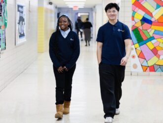 Two students at UCHS AMS in the Bronx walk through a school hallway